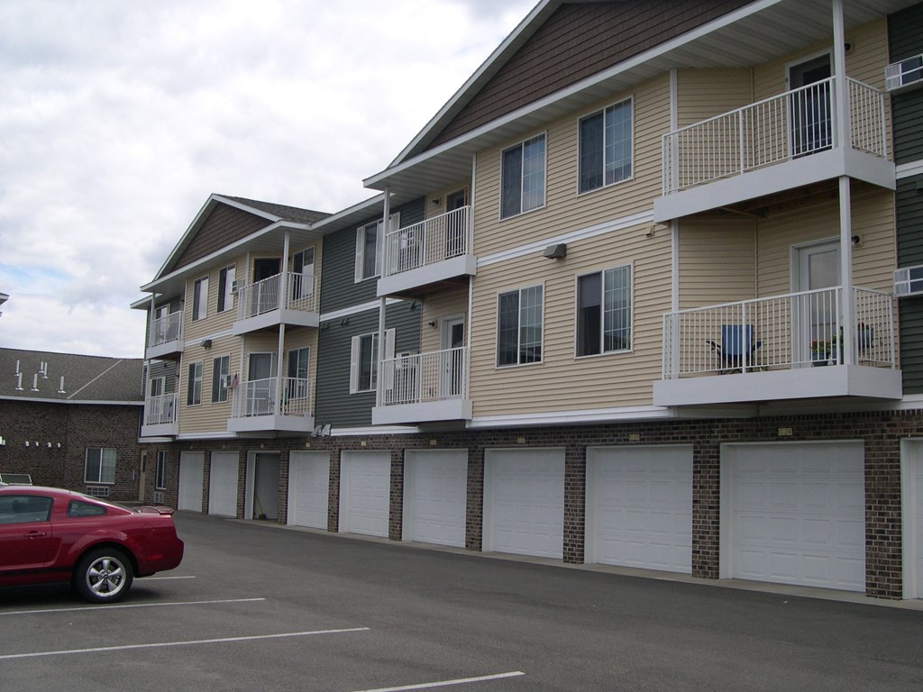 an empty parking lot in front of a building with white garage doors