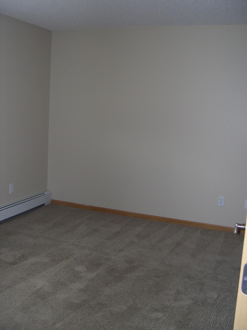 an empty room with a carpeted floor and a white wall