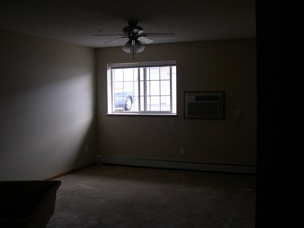 an empty room with a window and a ceiling fan