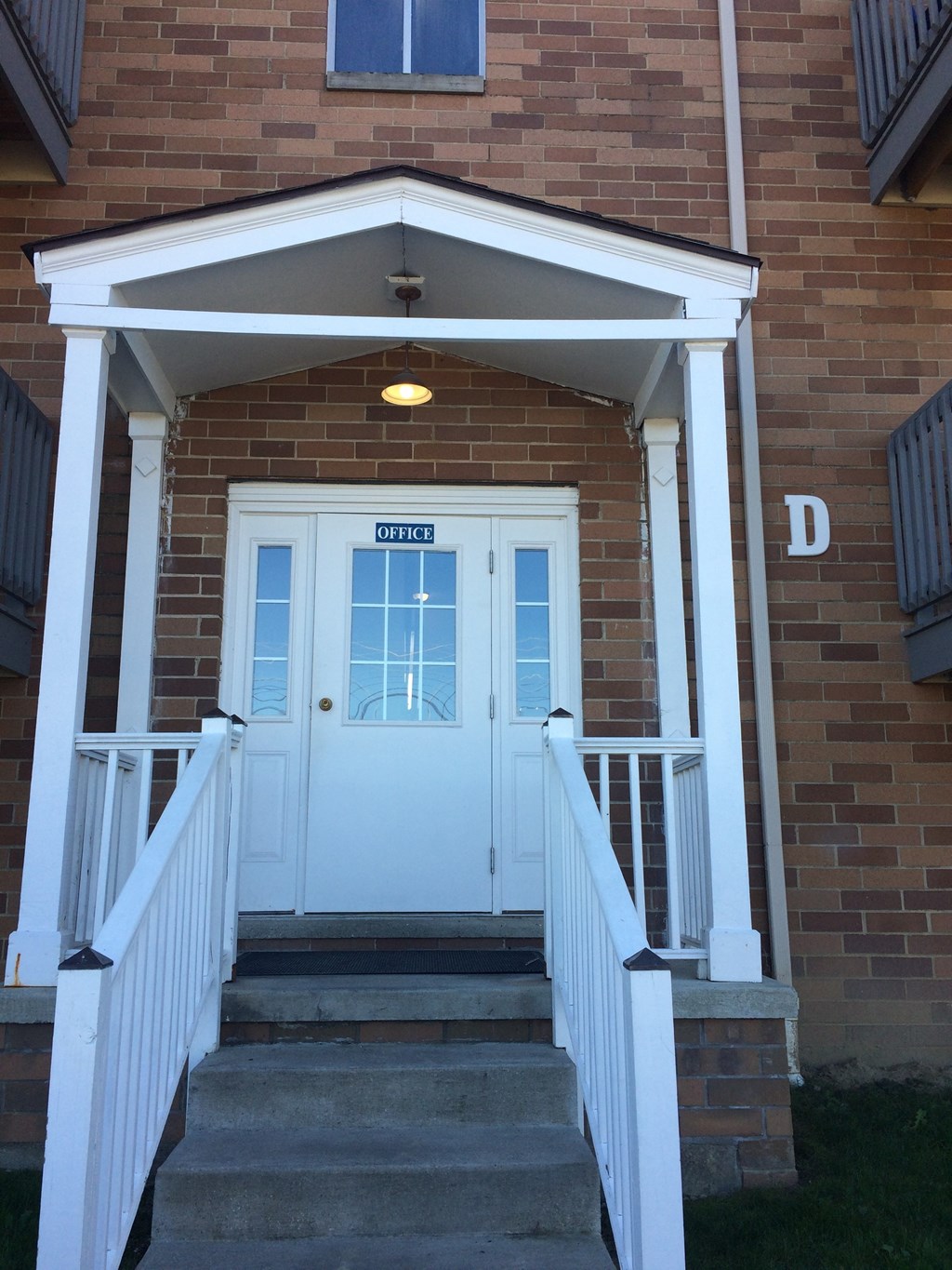 the front porch of a brick house with a white door