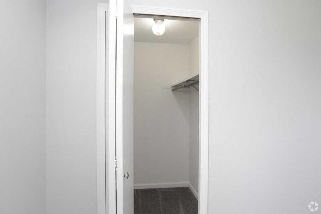 an empty closet in a home with white walls and a white door