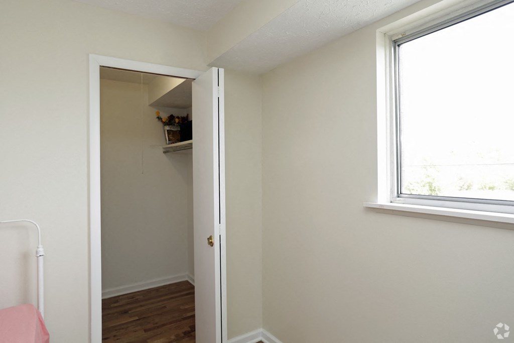 an empty bedroom with a closet and a window