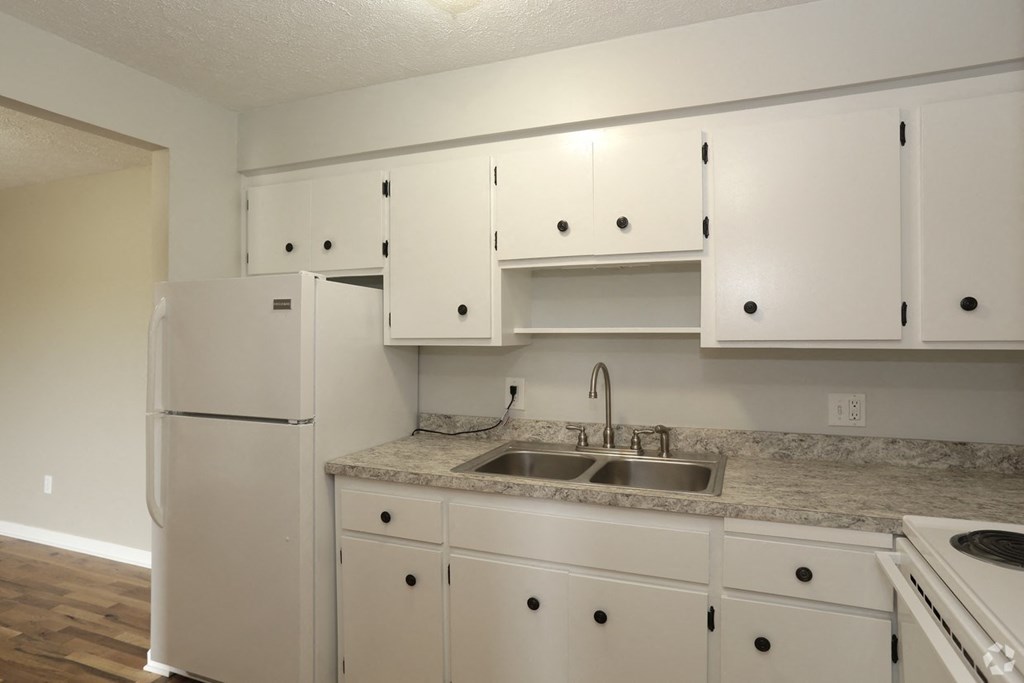 a kitchen with white cabinets and a sink and a refrigerator