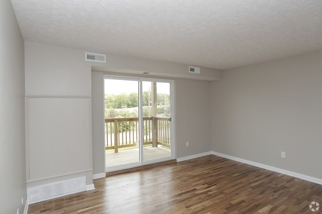 an empty living room with a sliding glass door to a balcony