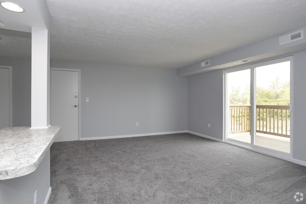 an empty living room with a balcony and a window