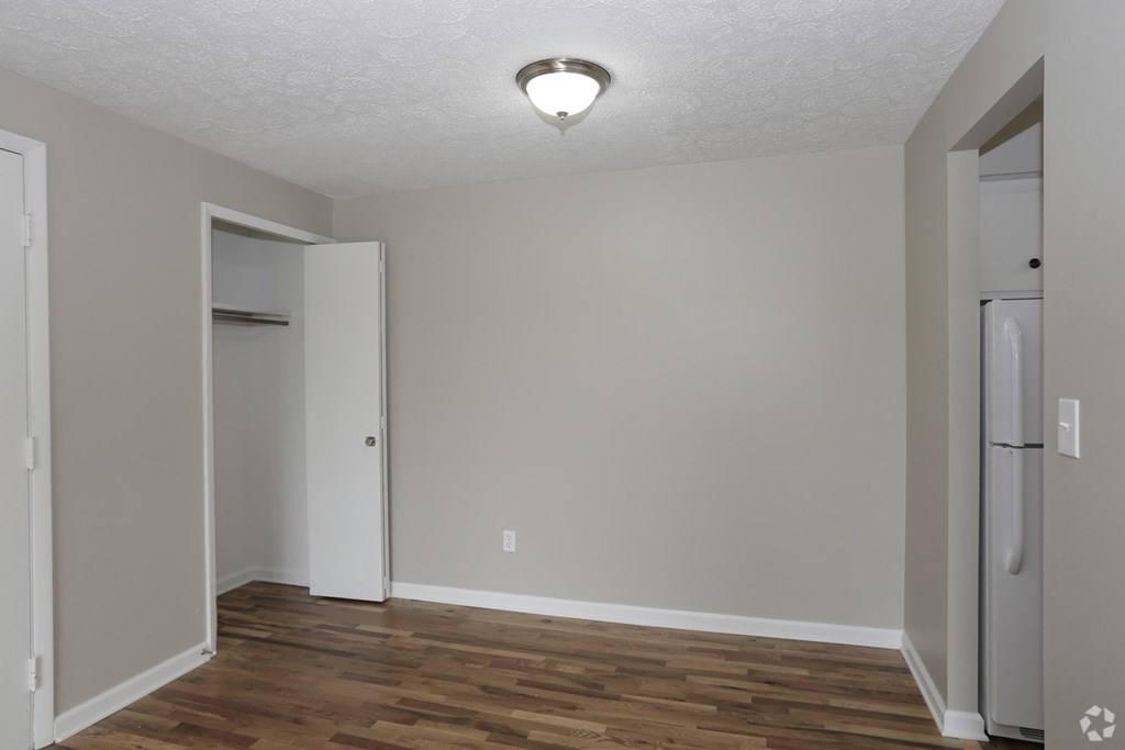 an empty living room with wood flooring and a refrigerator