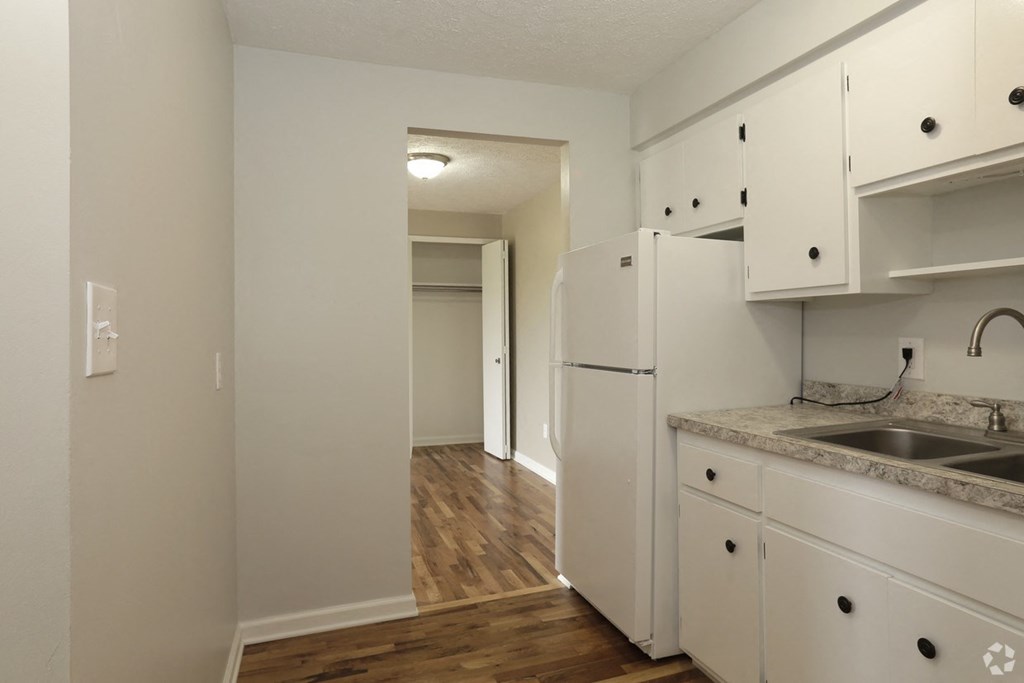 an empty kitchen with white cabinets and a white refrigerator