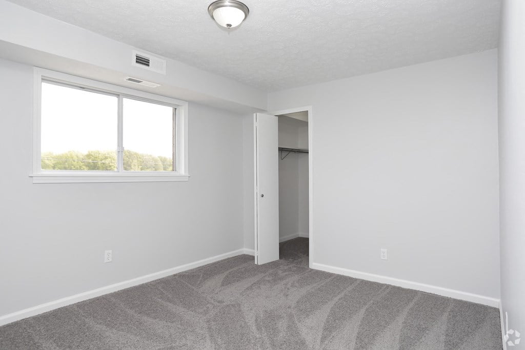 an empty living room with a window and a closet