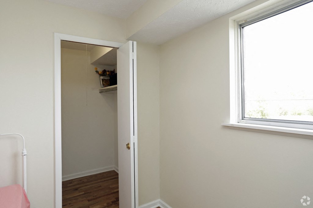 an empty bedroom with a closet and a window