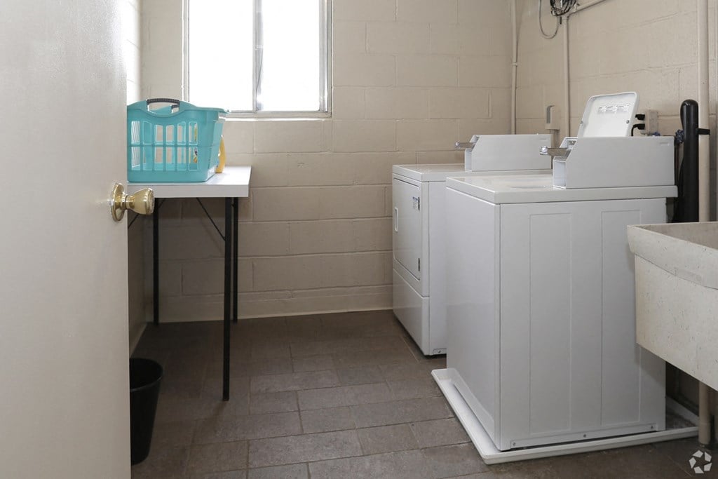 a laundry room with two washing machines and a sink and a window