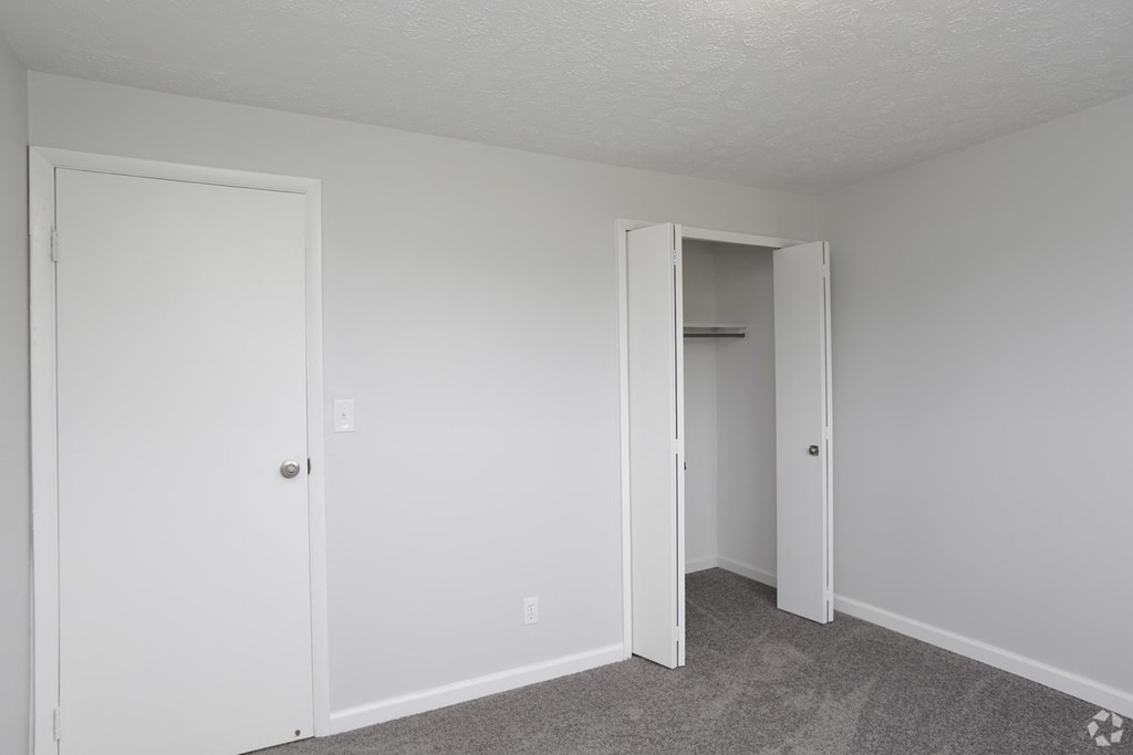 an empty bedroom with white walls and a closet