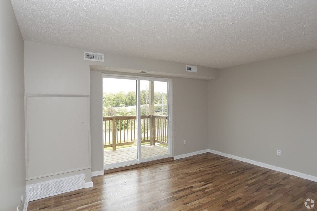 an empty living room with a sliding glass door to a balcony