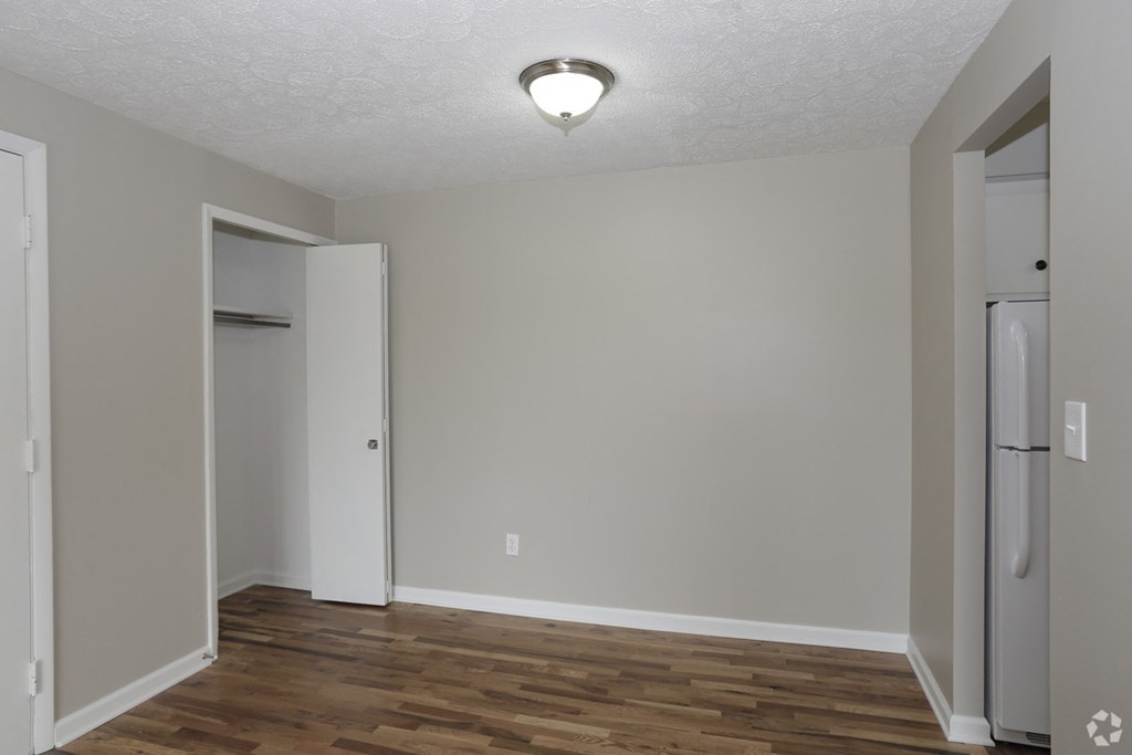an empty living room with wood flooring and a door to a closet