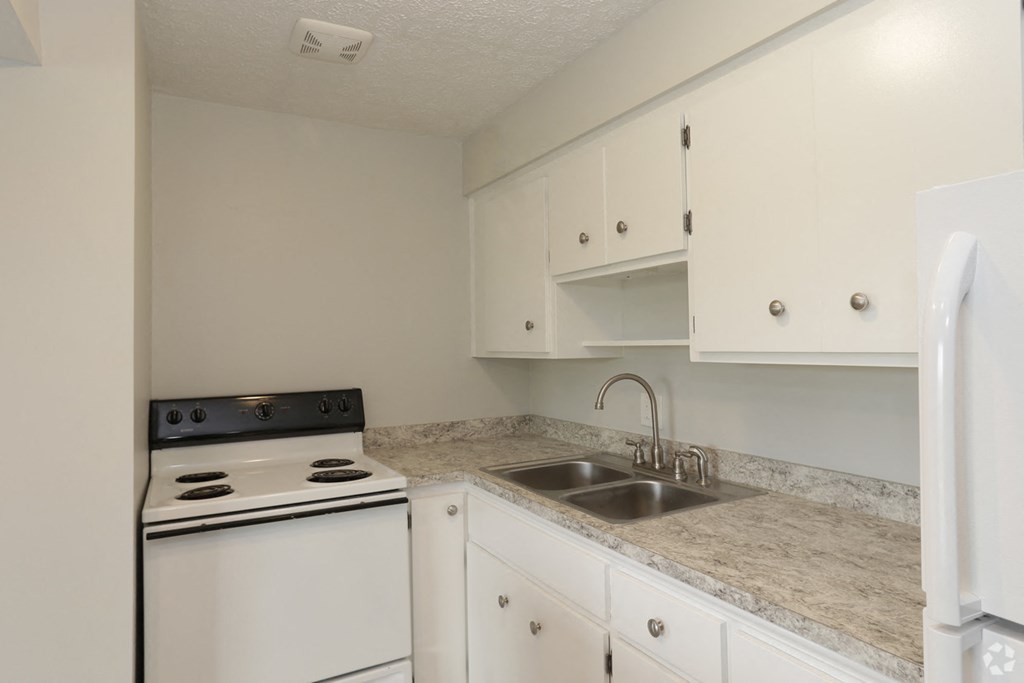 a kitchen with white appliances and granite counter tops and white cabinets
