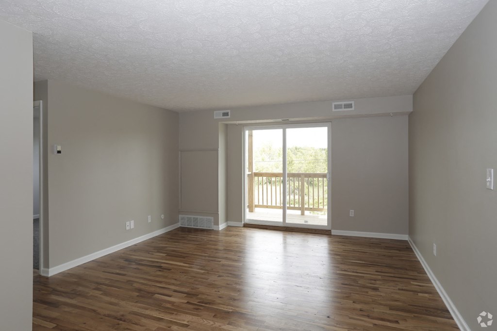 an empty living room with wooden floors and a sliding glass door