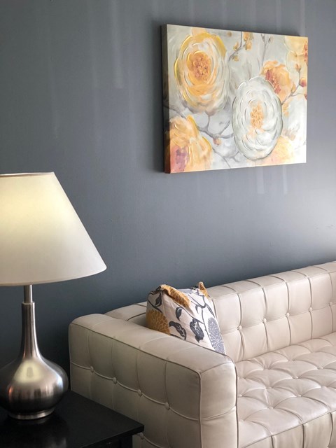 a living room with a white couch and a painting of roses
