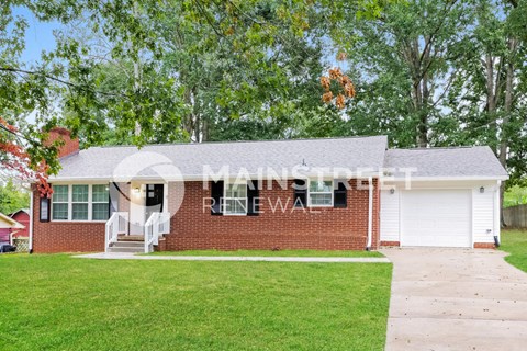 a brick house with a porch and a lawn