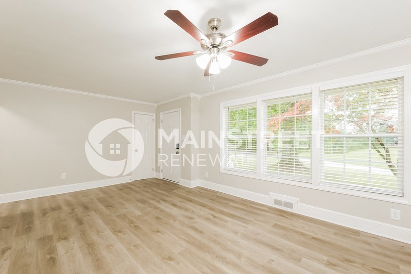 a living room with a large window and a ceiling fan