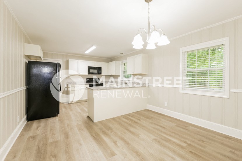 a studio apartment with a kitchen and a black refrigerator