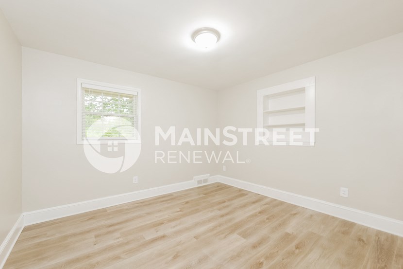 a room with a hardwood floor and white walls and a window