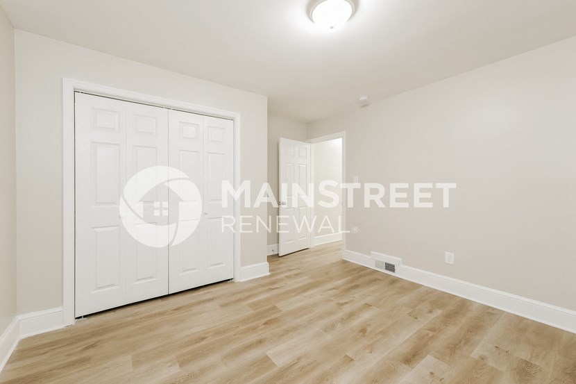 a studio apartment with a white closet and a white door