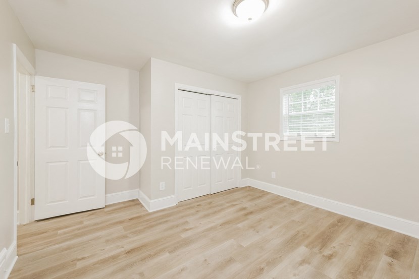 a renovated living room with white walls and wood floors