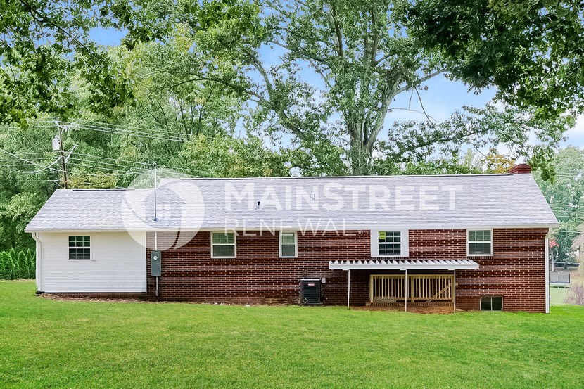 a small brick farm house with a large tree in front of it