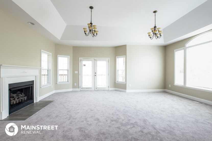 an empty living room with a fireplace and chandeliers
