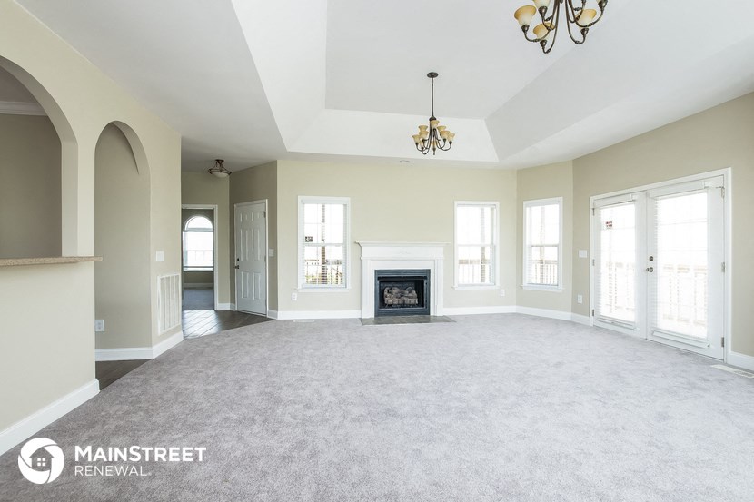 an empty living room with a fireplace and a chandelier
