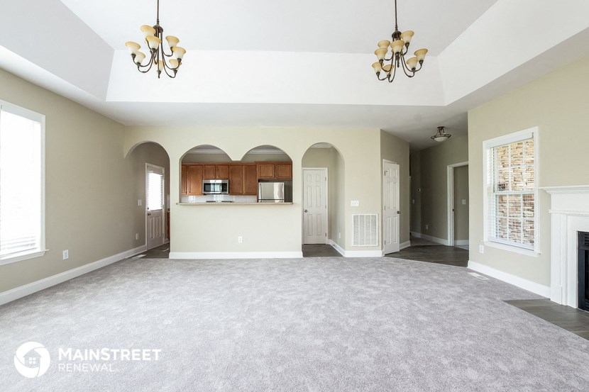 an empty living room with a fireplace and a kitchen