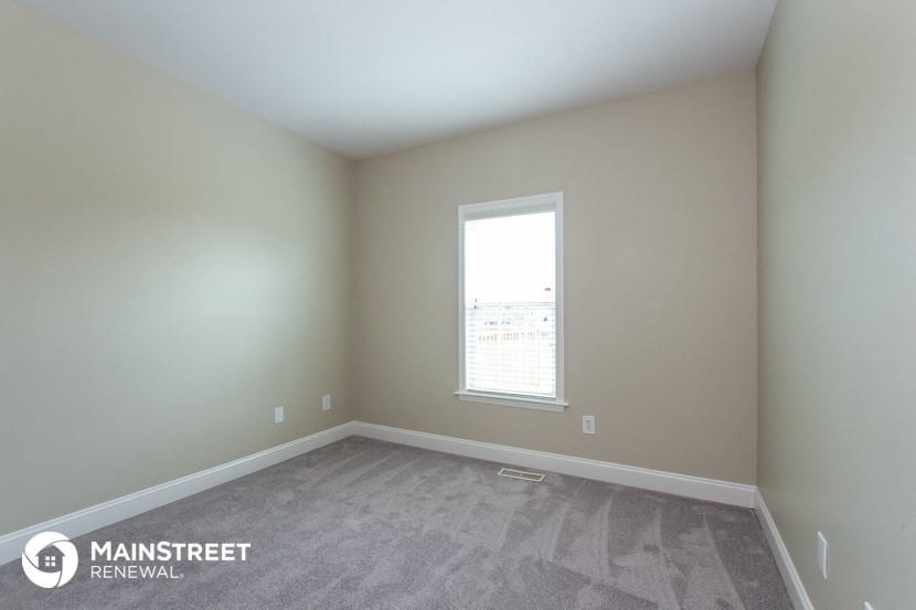 a bedroom with a window and a carpeted floor