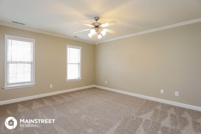 the master bedroom with carpeted flooring and a ceiling fan