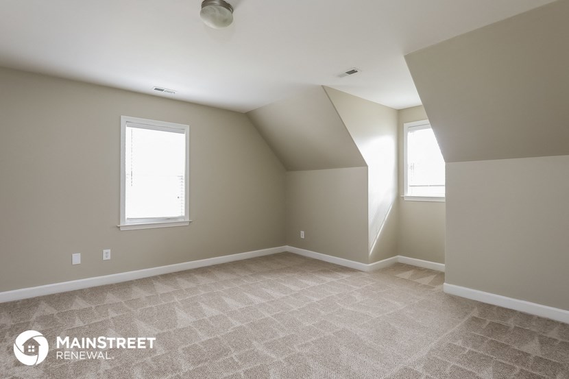 the upstairs bedroom with carpet and two windows