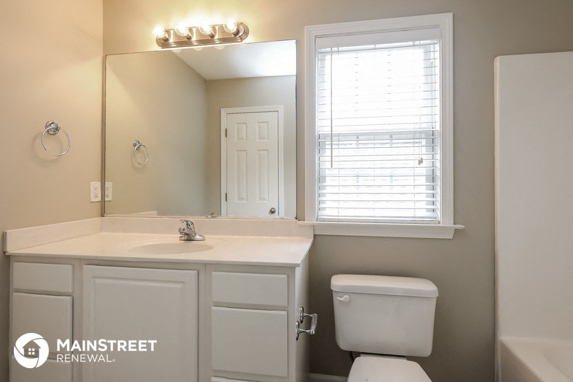 a bathroom with a toilet sink and mirror and a window