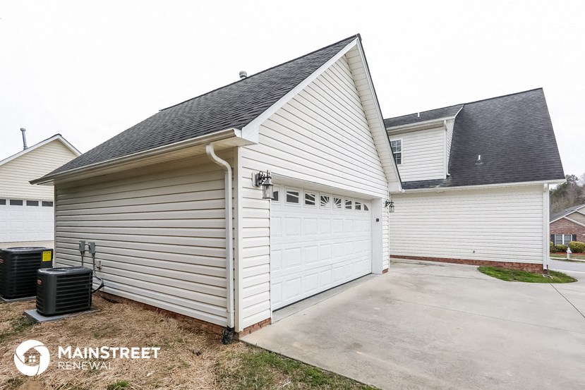 the driveway and garage of a white house with a garage door