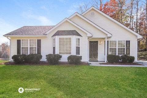 a white house with black shutters and a lawn