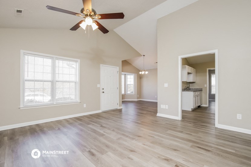 the living room and kitchen of an empty house with a ceiling fan