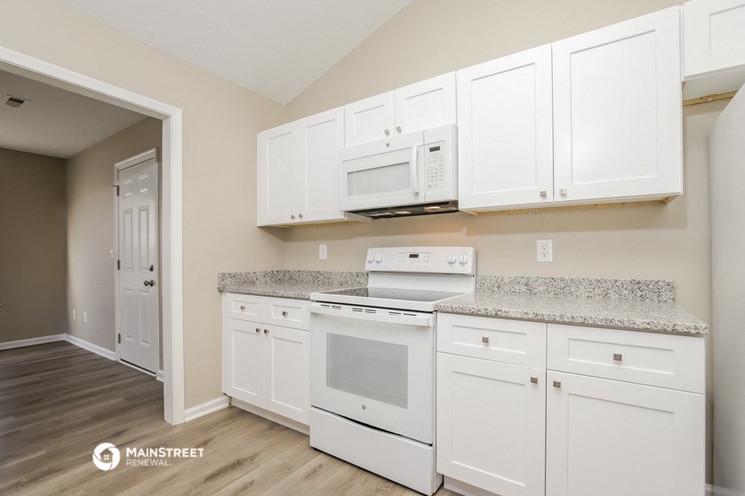 a kitchen with white cabinets and white appliances and granite counter tops