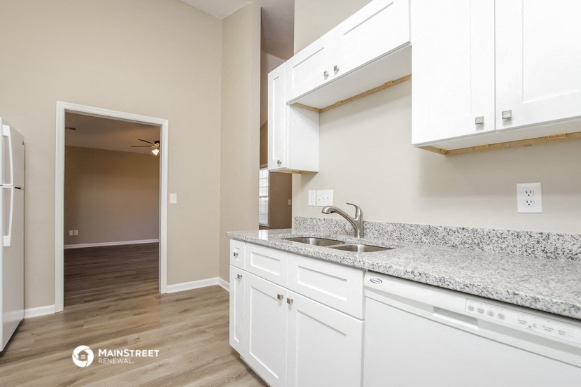 an open kitchen with white cabinets and granite counter tops