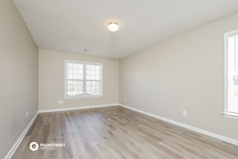 the spacious living room with hardwood flooring and two windows