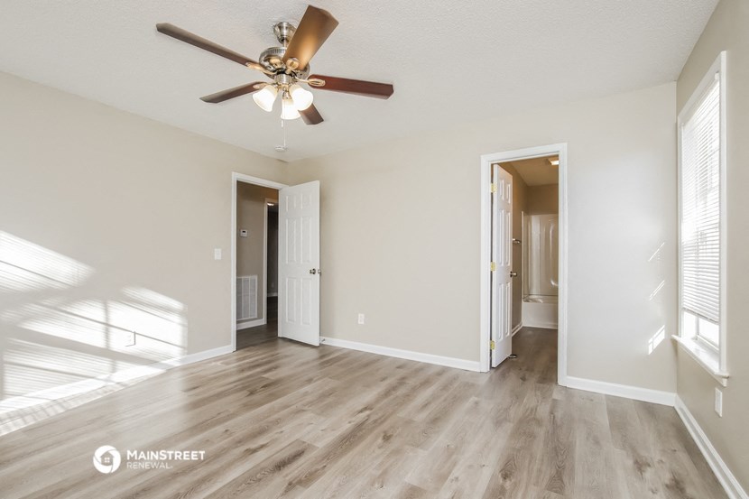 the spacious living room with ceiling fan and hardwood flooring