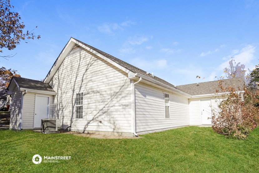 the side of a white house with a grass yard and a garage