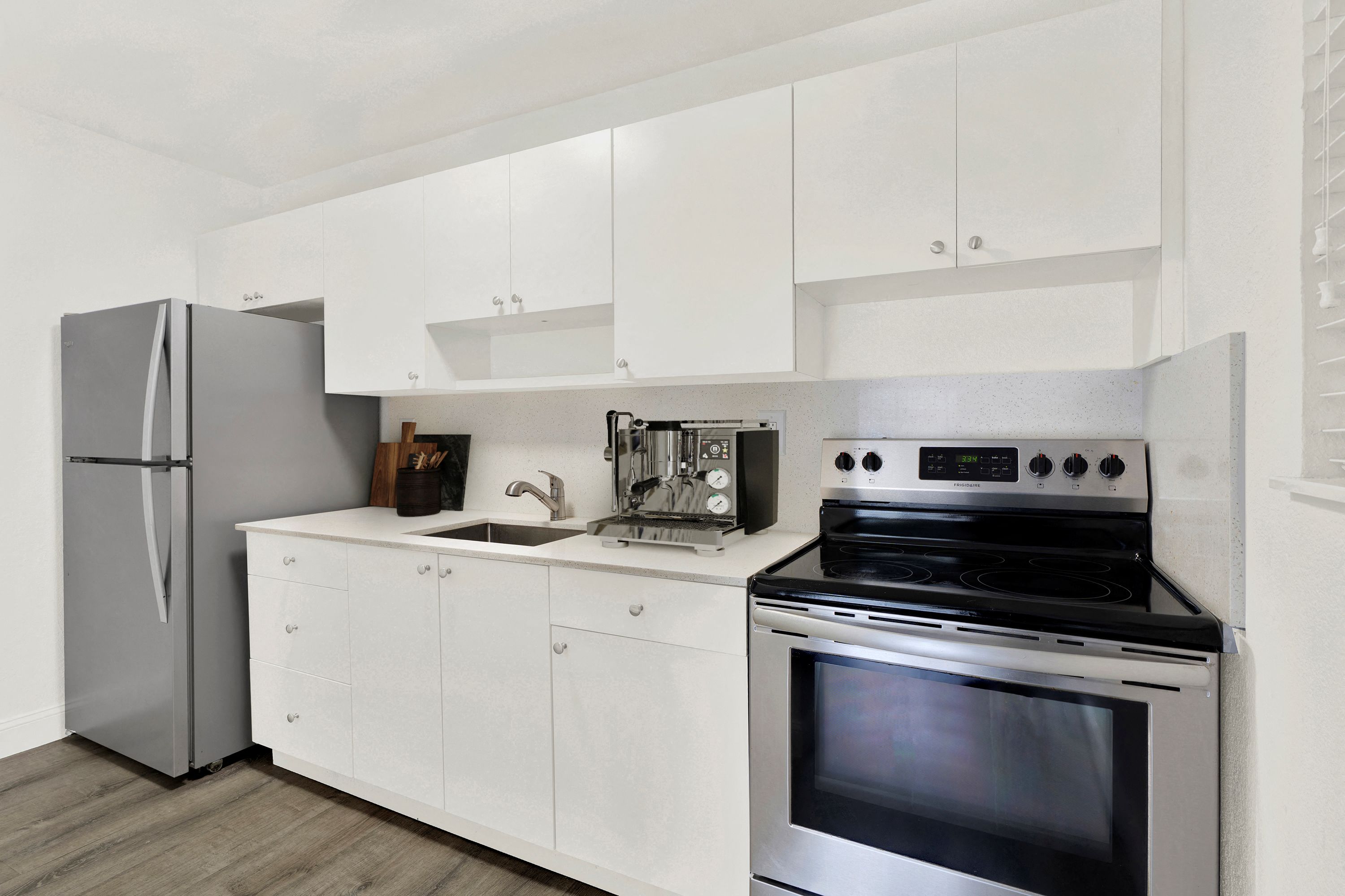 A modern kitchen with a stainless steel oven and white cabinets.
