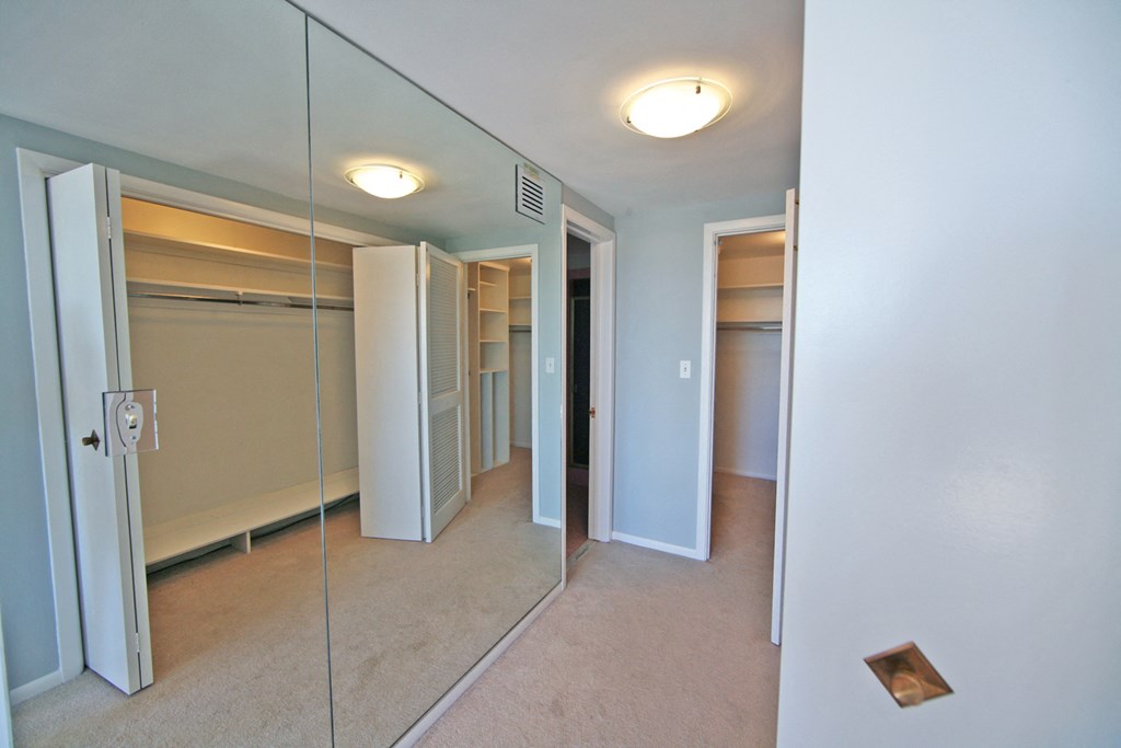 a bedroom with mirrored closet doors and a carpeted floor