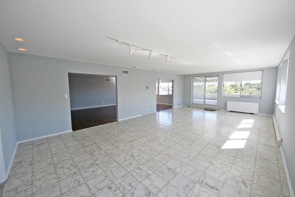 an empty living room with white marble flooring and white walls