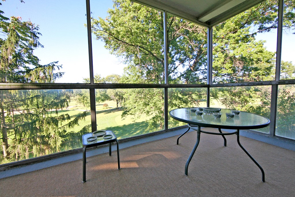 a screened in porch with a table and a chair
