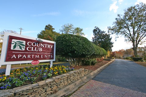 a sign for the country club apartments on the side of a road