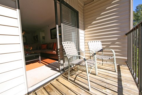 a small porch with two white chairs and a sliding glass door