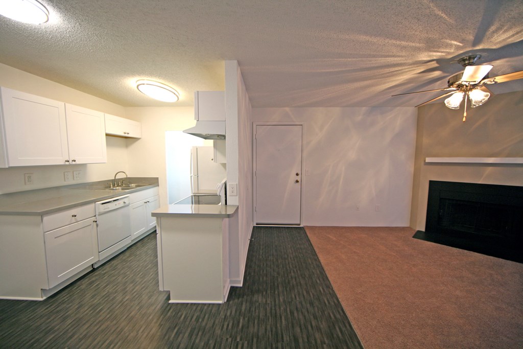 a kitchen and living room with a fireplace and white cabinets
