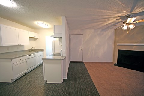 a kitchen and living room with a fireplace and white cabinets